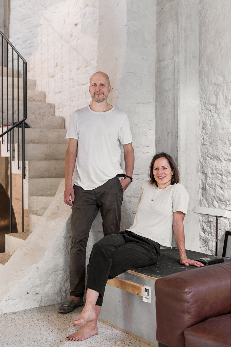 Porträtbild der Bauherren neben der Treppe, Architekt Andreas Bründler steht neben seiner Frau Sandra, die neben ihm sitz.