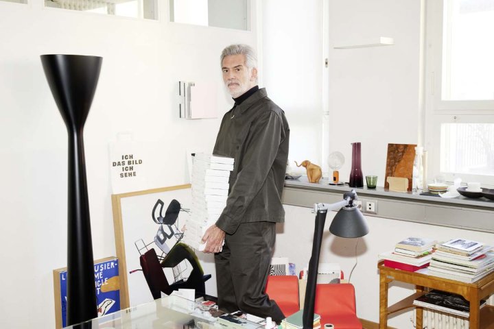 Der Designer Alfredo Häberli trägt ein Stapel von Bücher in einem Atelier herum.