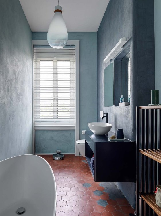 Ein Foto eines Badezimmers. Die Wände wie auch das Bad-Gestell sind blau. im Ecken befindet sich eine Badewanne.