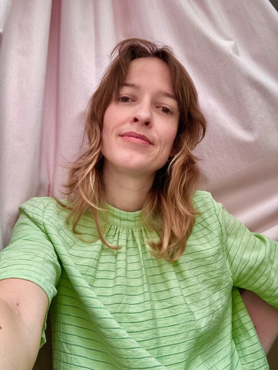 Tina Bobbe ist Industriedesignerin und Designforscherin. Auf diesem Bild trägt sie ein hellgrünes T-Shirt und posiert vor einer rosa Wand.